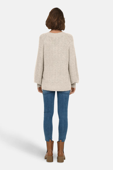 Pull à col en V écru de ONLY® avec motif en losange, porté avec un jean et des bottines marron.
