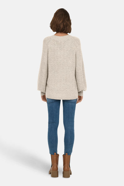 Pull à col en V écru de ONLY® avec motif en losange, porté avec un jean et des bottines marron.