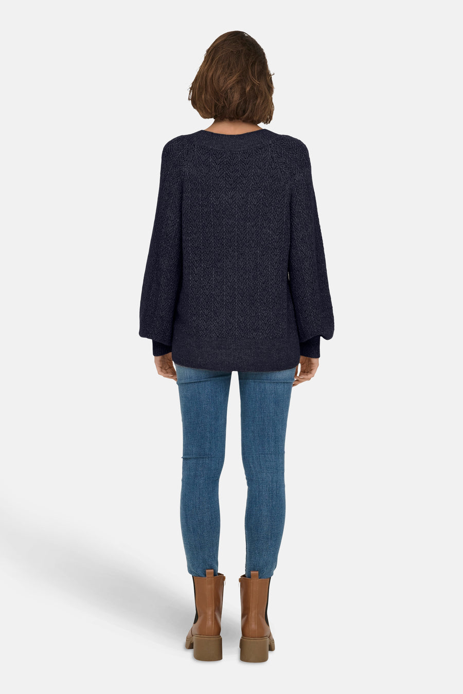 Pull col V bleu de ONLY, porté avec un jean slim et des bottines marron, vue de dos.
