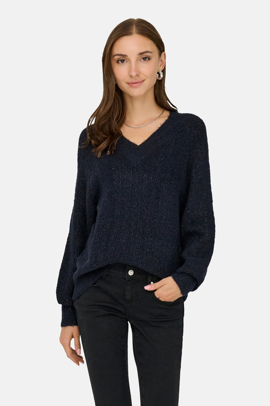 Pull bleu à col en V de ONLY®, porté avec un pantalon noir et des bijoux argentés.
