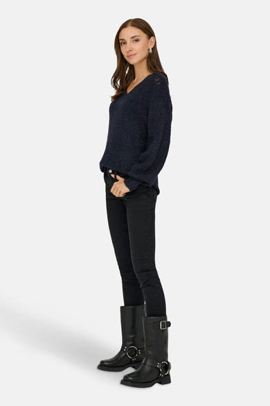 Pull à col en V bleu de ONLY, avec une texture tricotée, porté avec un jean noir et des bottes motardes.
