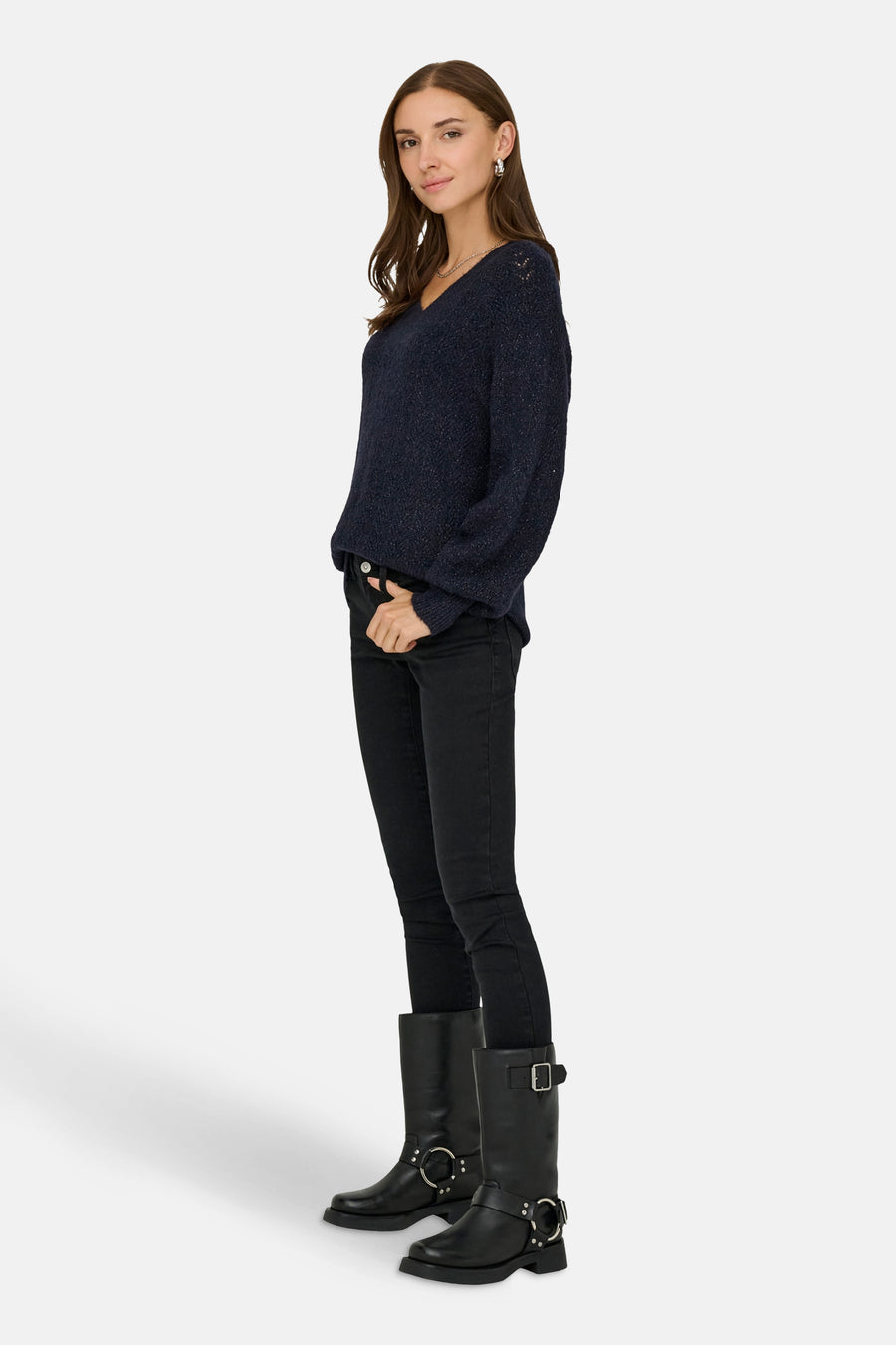 Pull à col en V bleu de ONLY, avec une texture tricotée, porté avec un jean noir et des bottes motardes.
