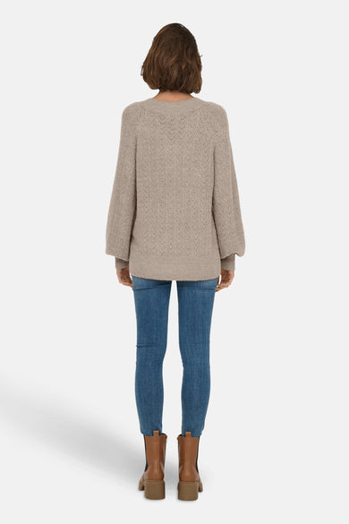 Pull à col en V beige de ONLY®, porté avec un jean bleu et des bottines marron à talons, vue de dos.