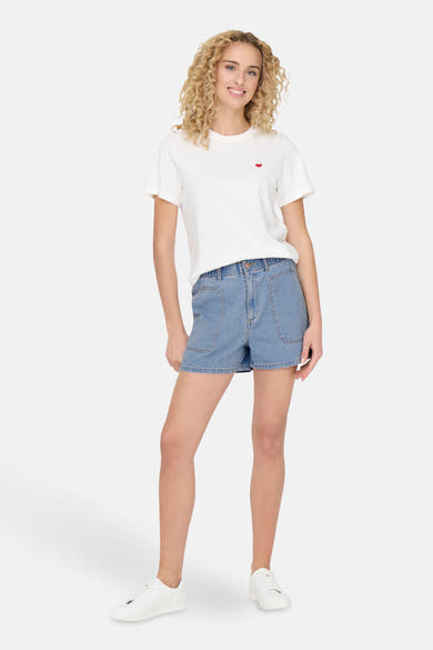 Short en denim bleu clair de JDY, porté avec un t-shirt blanc à motif cœur.
