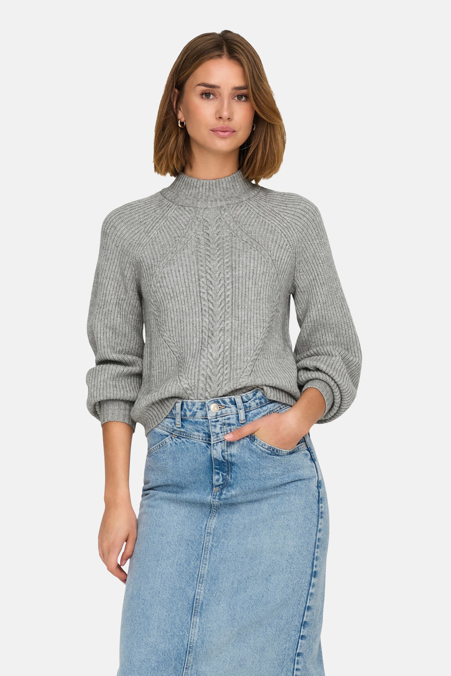 Pull à col roulé gris de ONLY, avec motif torsadé sur le devant, porté avec une jupe en jean.

