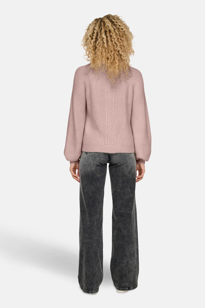 Pull à col roulé rose ONLY® avec un motif de torsades sur le dos, porté avec un jean gris.