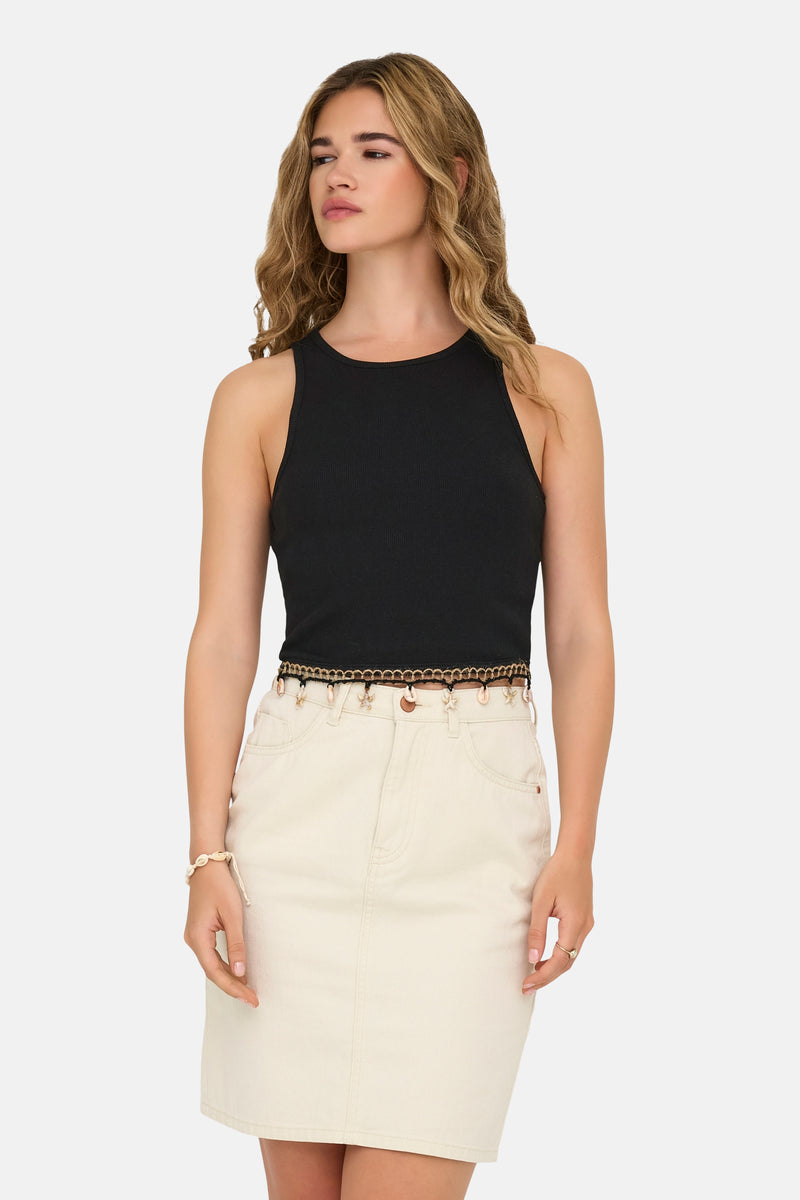 Débardeur noir ONLY®, côtelé, porté avec une jupe claire et une ceinture décorative à coquillages.
