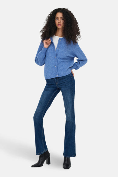 Blauwe geribbelde gebreide cardigan van JDY, gedragen over een wit T-shirt en een uitlopende jeans met zwarte enkellaarsjes.