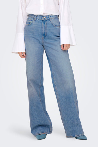 Jean large bleu moyen de ONLY, porté avec une chemise blanche à manches évasées et des escarpins bleus.