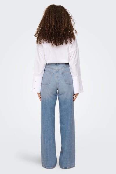 Jeans larges en denim bleu moyen de ONLY, portés avec une chemise blanche boutonnée.