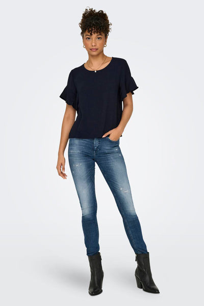 Blouse bleu à manches courtes de JDY, portée avec un jean et des bottines noires à talons.