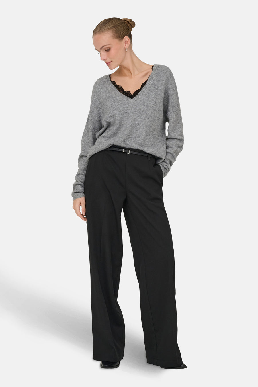 Grijze V-hals trui van ONLY, met zwarte kanten bies, gedragen met een zwarte high-waist broek.