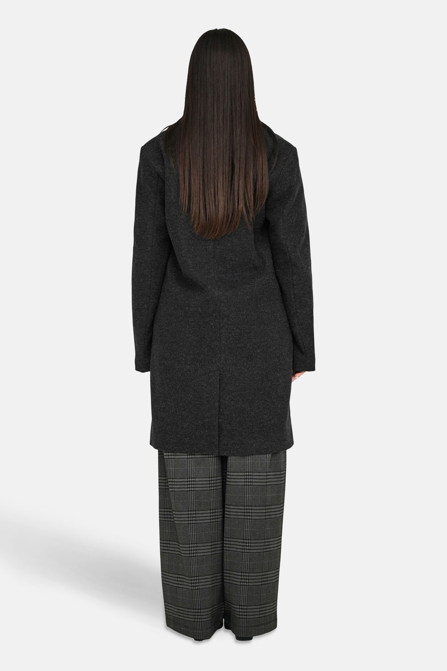 Veste longue noire de JDY avec un col tailleur et un motif à carreaux sur le pantalon porté.