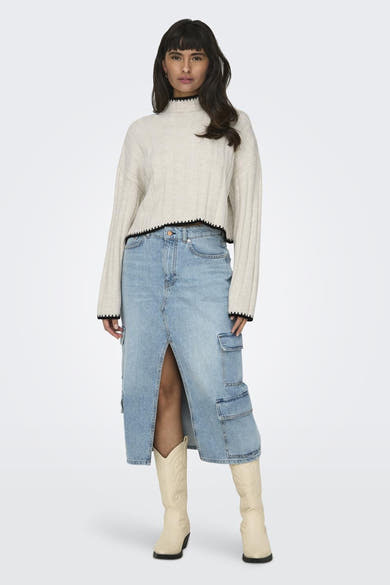 Pull à col roulé écru de ONLY, à texture côtelée, porté avec une jupe en jean à fente et des bottes blanches.
