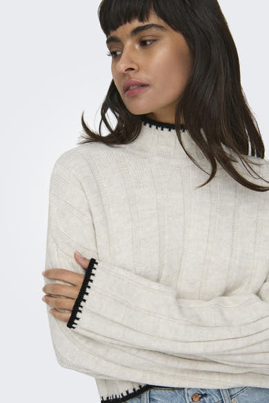 Pull à col roulé en tricot de ONLY®, couleur écru avec bordure noire, porté avec un jean décontracté.