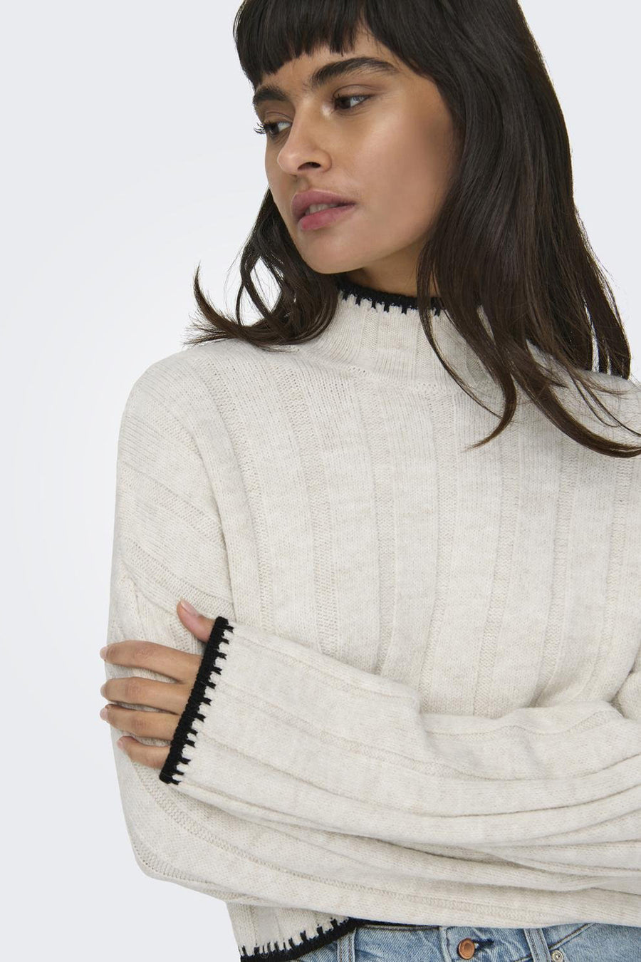 Pull à col roulé en tricot de ONLY®, couleur écru avec bordure noire, porté avec un jean décontracté.