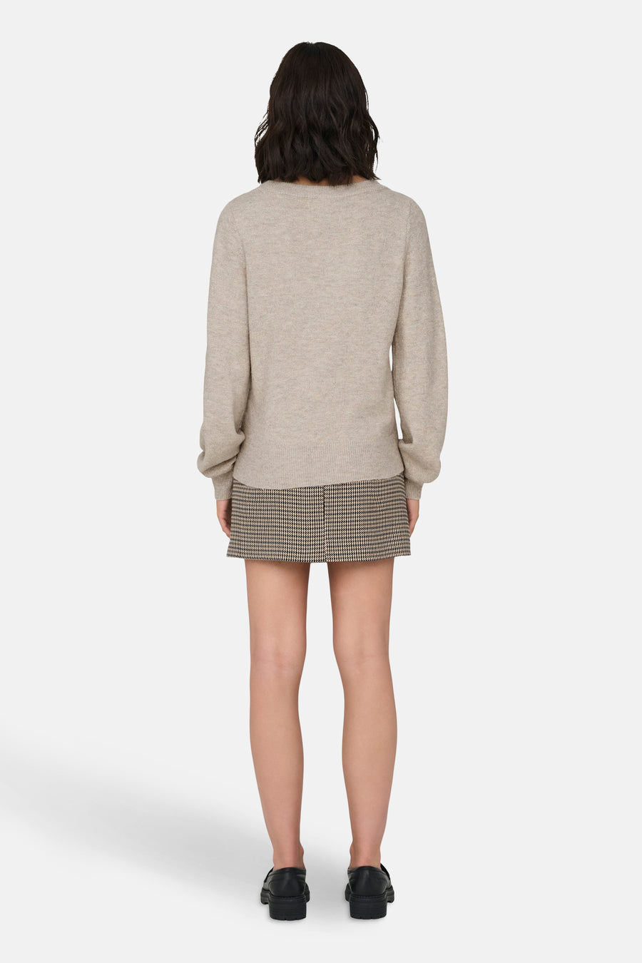 Beige ronde hals trui van JDY, gedragen met een geruite rok en zwarte schoenen.