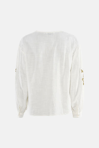 Blouse blanche à manches longues de ONLY, avec broderie florale dorée sur les manches.
