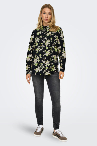 Chemisier à manches longues multicolore de JDY, avec un motif floral sur fond noir, porté avec un jean gris et des baskets marron.

