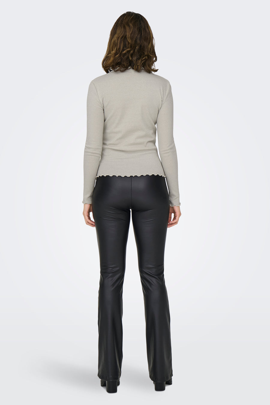 T-shirt à manches longues écru de ONLY, côtelé avec ourlet ondulé, porté avec un pantalon noir taille haute.

