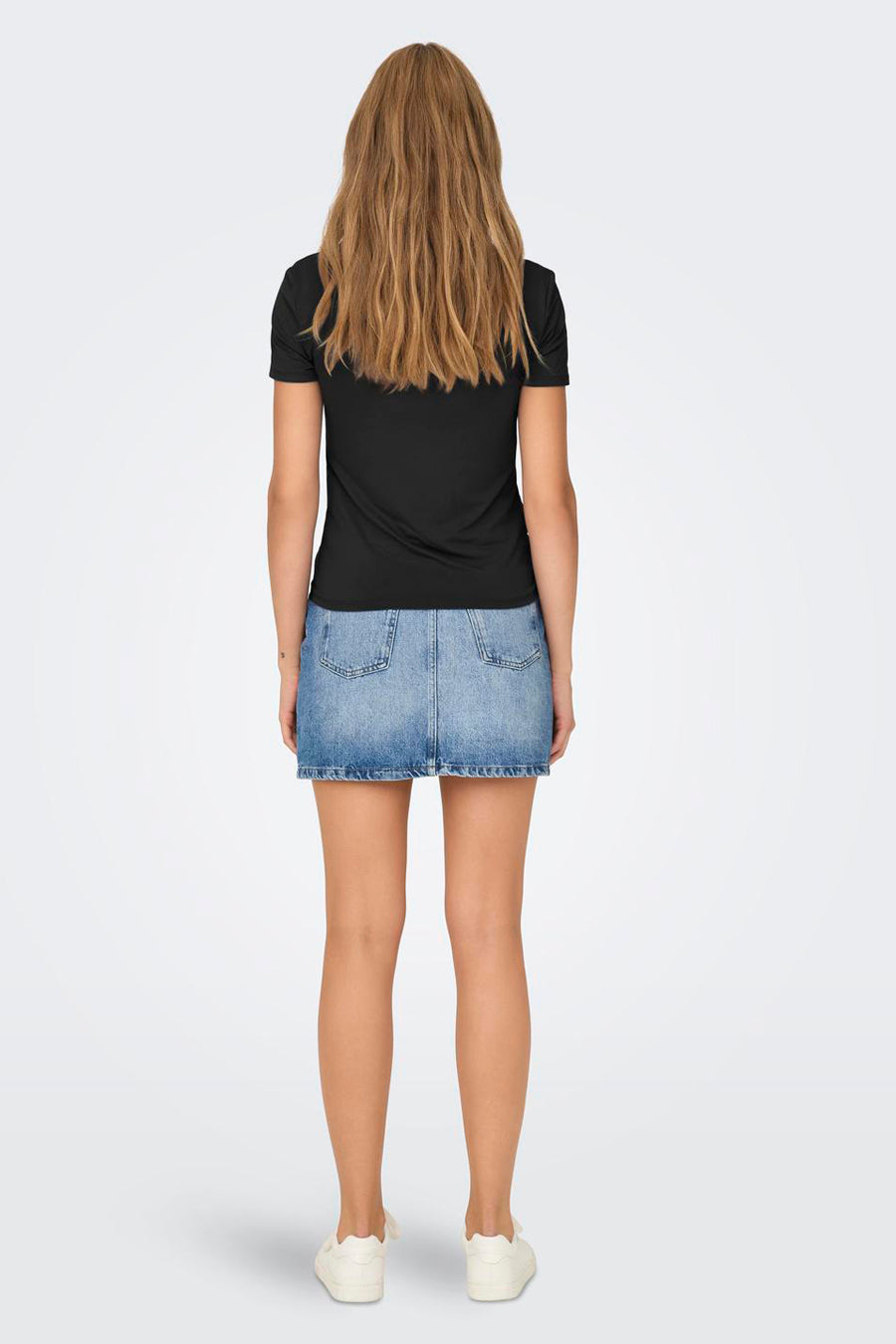 Zwarte top van ONLY®, gedragen met een spijkerrok en witte schoenen, van achteren gezien.