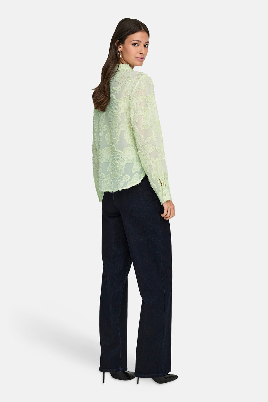 JDY groen overhemd met lange mouwen, met textuurpatroon, gedragen met donkerblauwe jeans en zwarte hakken.