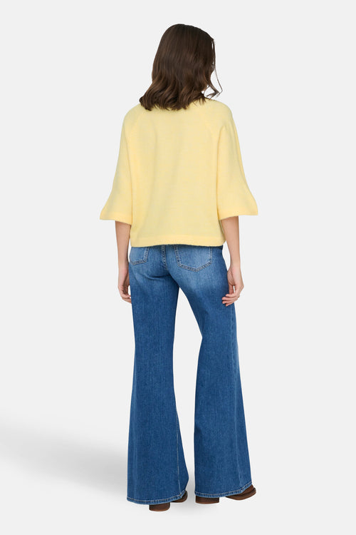 Pull jaune à col rond de ONLY®, porté avec un jean évasé bleu.
