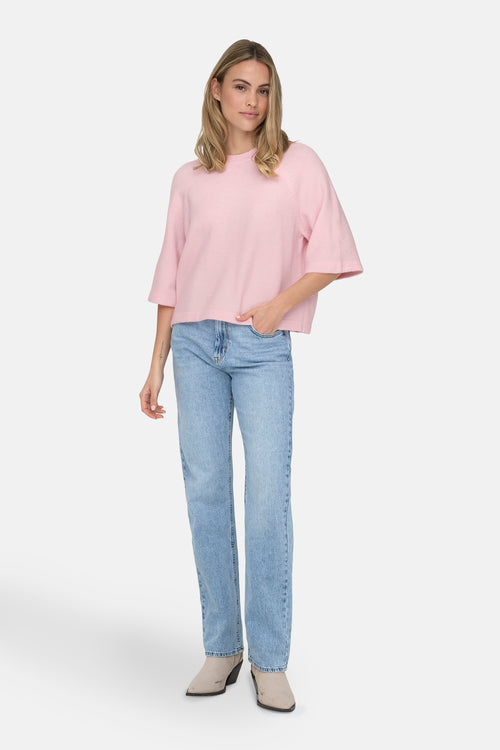 Pull à col rond rose par ONLY, porté avec un jean bleu clair et des bottines en daim.