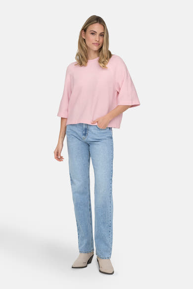 Roze trui met ronde hals van ONLY, gedragen met een lichtblauwe jeans en suède enkellaarsjes.
