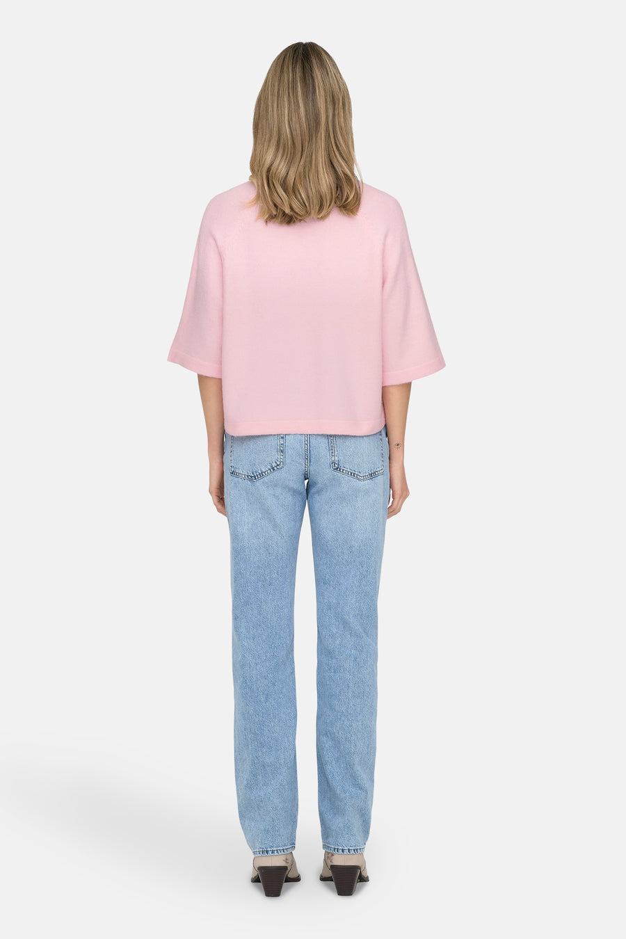Roze trui met ronde hals ONLY®, gedragen met een blauwe spijkerbroek en bruine enkellaarsjes met hak, achterkant.