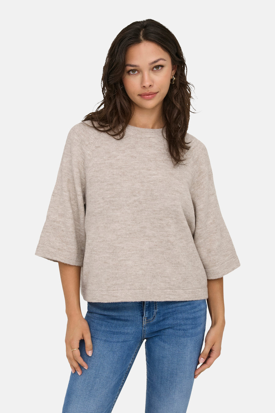 Beige ronde hals trui van ONLY, gedragen met een blauwe spijkerbroek en gouden oorbellen.