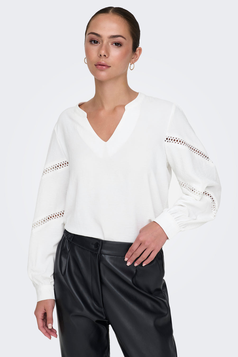 Wit overhemd met lange mouwen en V-hals van JDY, met uitgesneden details op de mouwen, gedragen met een zwarte broek.