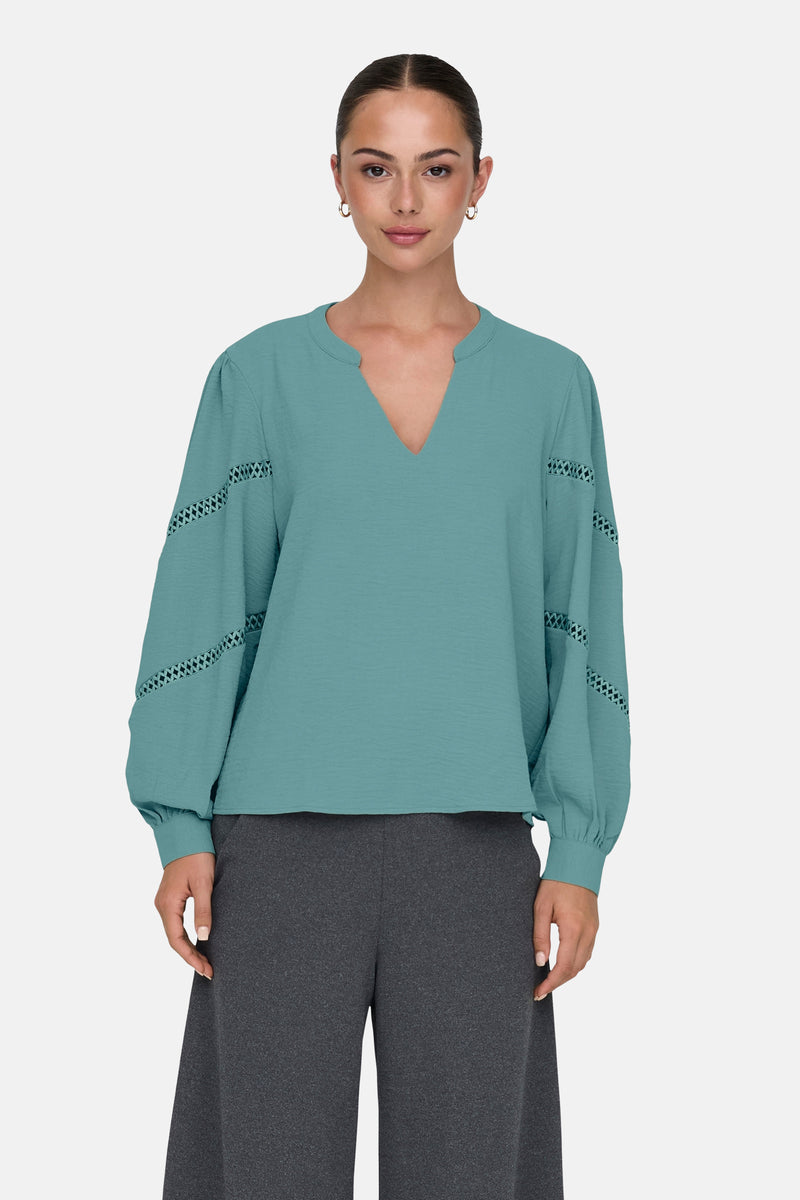Groen overhemd met lange mouwen van JDY, met uitgesneden details op de mouwen, gedragen met een grijze broek.
