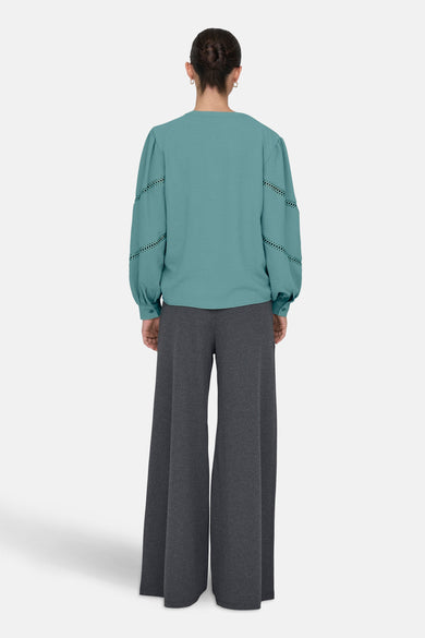 Chemisier à manches longues vert, de JDY, avec détails ajourés aux manches, porté avec un pantalon gris.