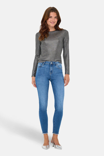 Grijze rondehals trui van ONLY, met metallic verticale strepen, gedragen met een blauwe jeans en zilveren pumps.