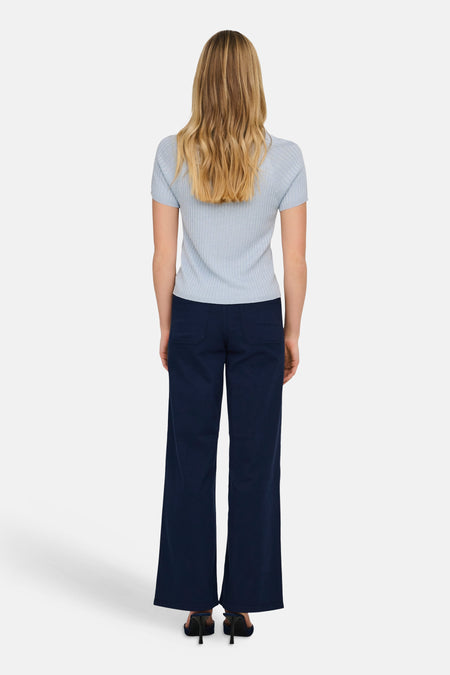 T-shirt bleu à manches courtes de JDY, texture côtelée, porté avec un pantalon bleu marine évasé et des escarpins.