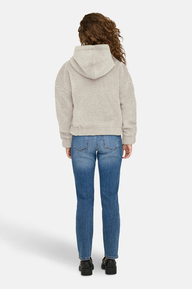 Korte ecru jas van ONLY, gedragen met een blauwe jeans en zwarte plateauzolen, van achteren gezien.