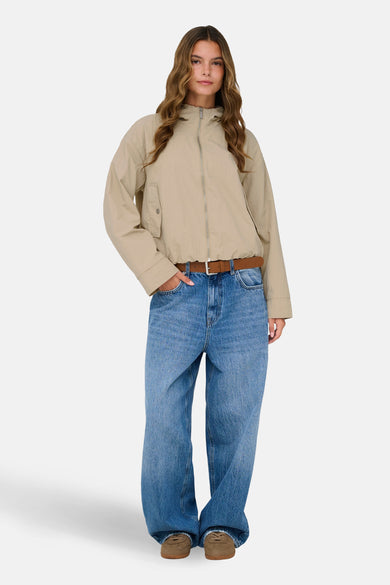 Veste courte beige de ONLY, portée avec un jean ample et une ceinture marron.