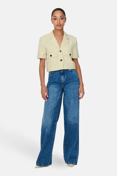 Chemise à manches courtes beige, de JDY, avec des poches plaquées et portée avec un jean taille haute.
