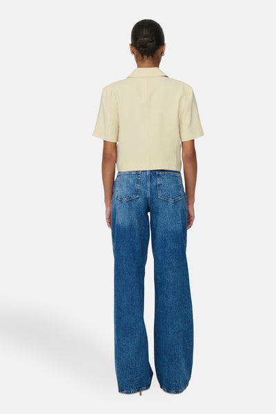 Chemise à manches courtes beige de JDY, vue de dos, portée avec un jean bleu ample.