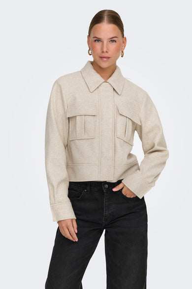 Veste courte écru de ONLY, avec poches à rabat, portée avec un jean noir.