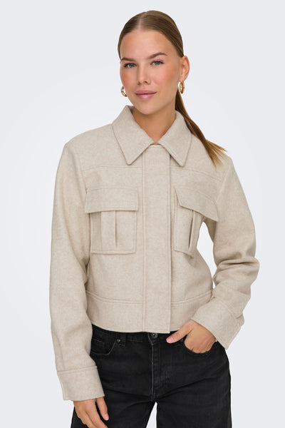 Veste courte écru de ONLY, avec poches plaquées et portée sur un jean noir.
