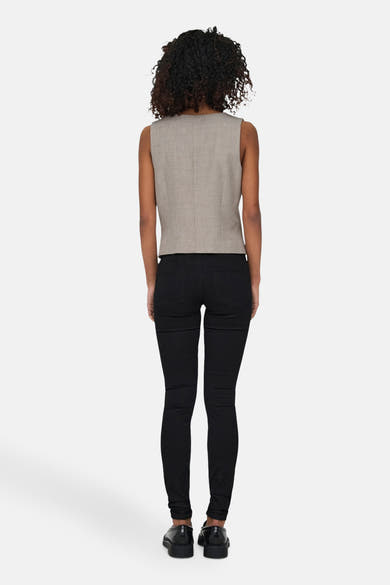 Beige blazer van ONLY, gedragen met een zwarte jeans, achtergezicht, met krullend haar.