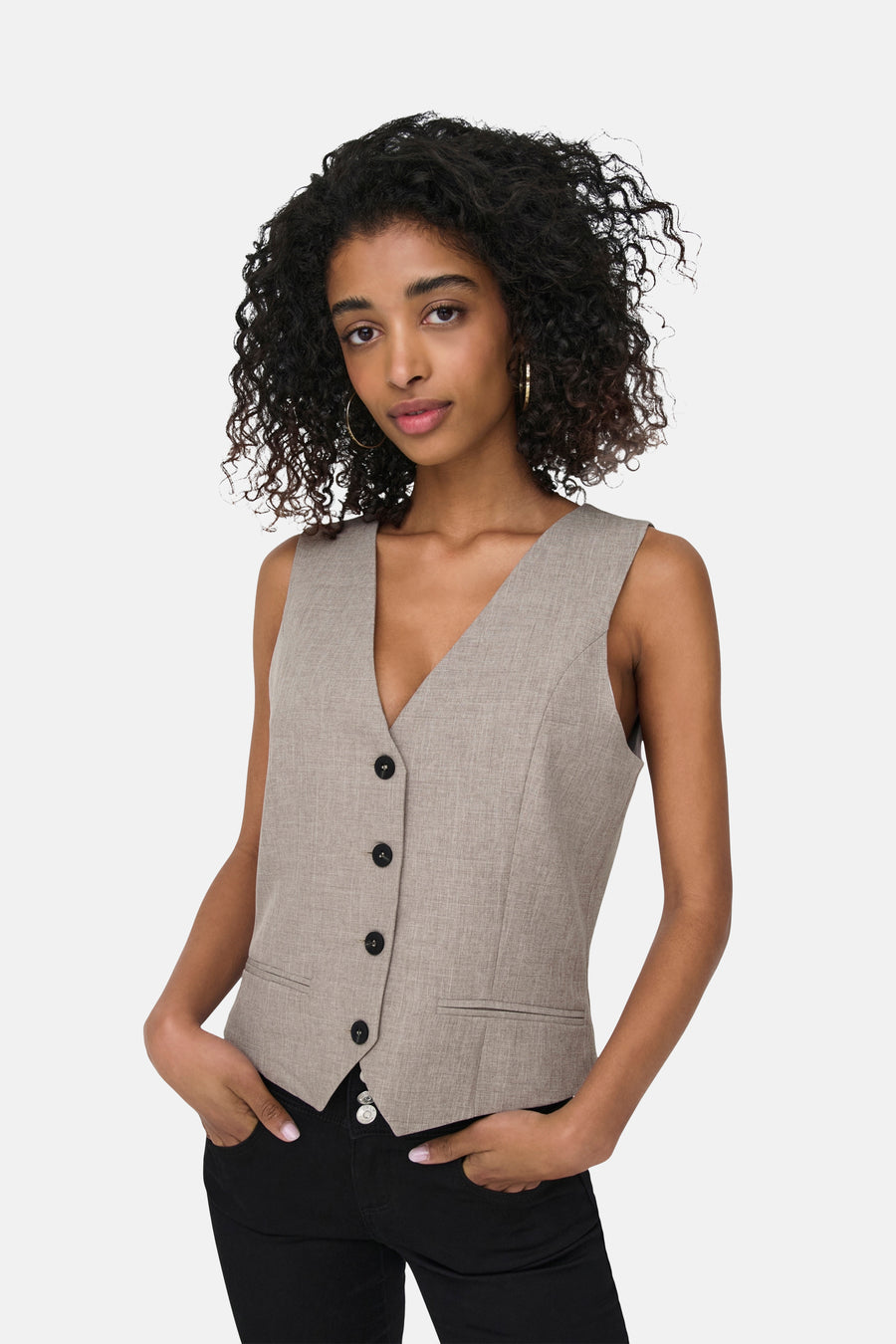 Beige blazer van ONLY®, gecropt model met knopen, gedragen met een zwarte jeans en gouden ringen.