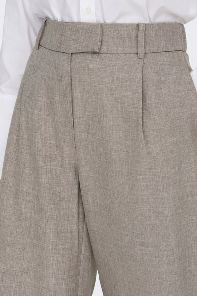 Beige kostuumbroek van ONLY®, met riem en duidelijke vouwen, gedragen met een wit overhemd.