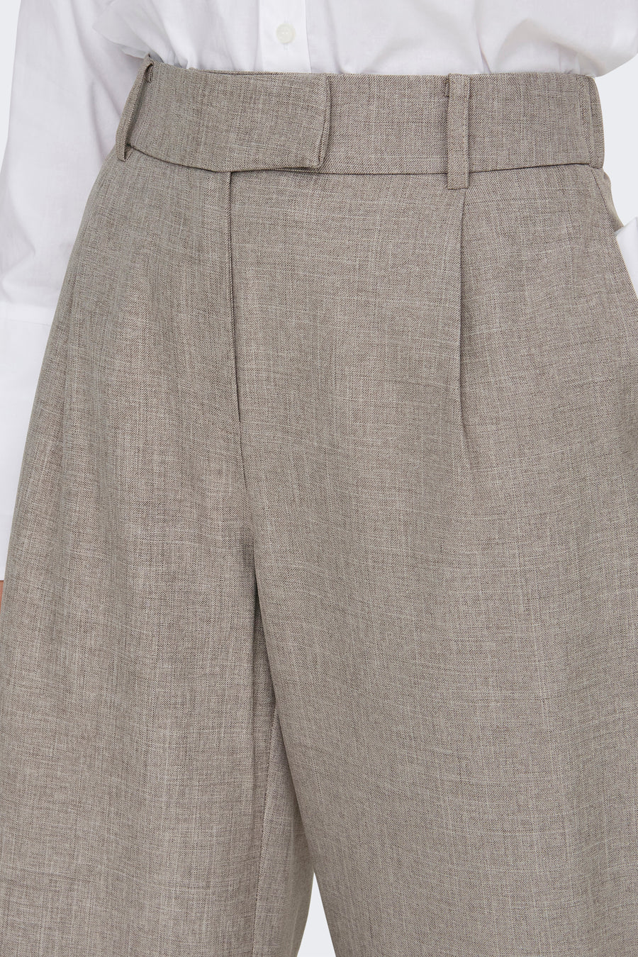 Beige kostuumbroek van ONLY®, met riem en duidelijke vouwen, gedragen met een wit overhemd.