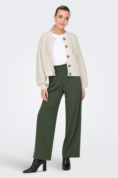 Cardigan écru en maille bouclée de JDY, porté sur un t-shirt blanc et un pantalon vert olive.
