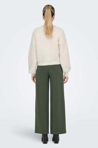 Cardigan écru de JDY, en maille bouclette douce, porté avec un pantalon vert ample et des bottines noires.
