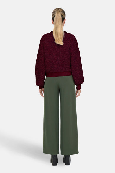 Bordeauxrode textuurcardigan van JDY, gedragen met een wijde groene broek en zwarte hakken.