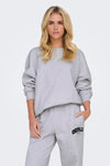Sweat col rond gris par ONLY®, porté par une femme, avec le logo Knoxville Leisure Club sur le pantalon.
